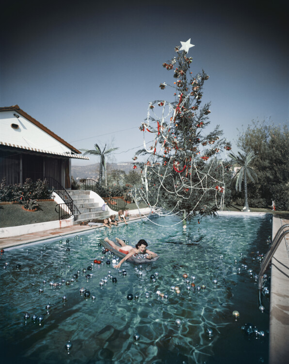 Ріта Ааронс, дружина фотографа Сліма Ааронса, плаває в басейні, прикрашеному плавальними кулями й різдвяною ялинкою, Голлівуд, 1954 рік