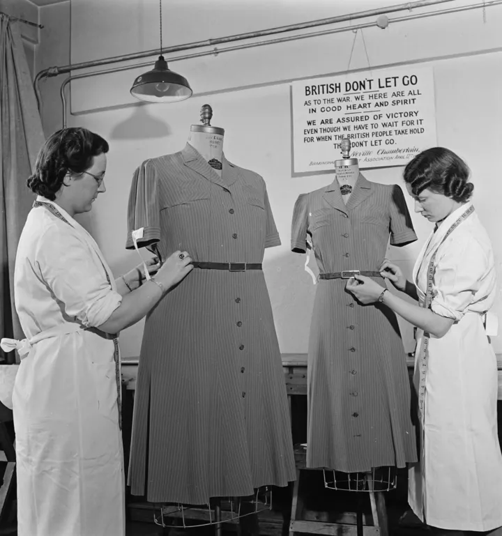 Дві працівниці швейної справи здійснюють останню перевірку двох нових утилітарних суконь, виготовлених на фабриці одягу Berkers у Лондоні під час Другої світової війни 17 травня 1940 року
